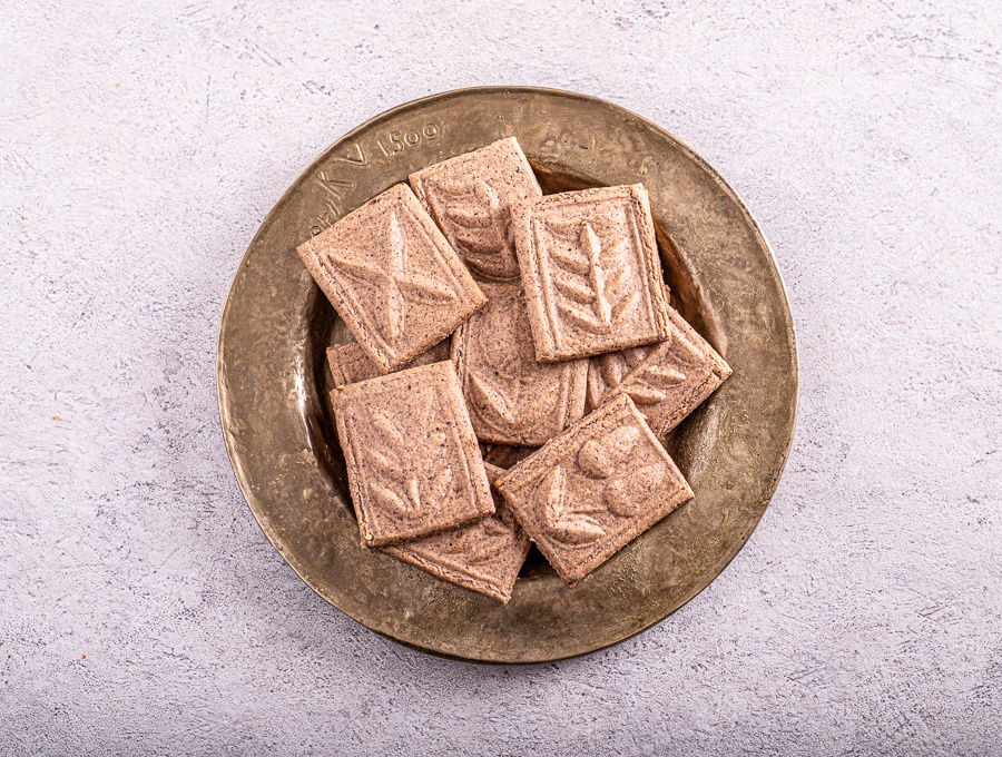 A plate of Paprenjaci, traditional Croatian Black Pepper Cookies, on a white surface.