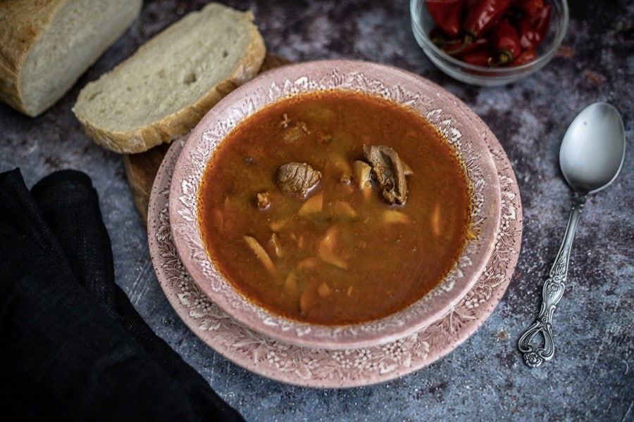 Traditional Croatian Food: A flavorful bowl of soup, paired perfectly with warm bread and a hint of spicy peppers.